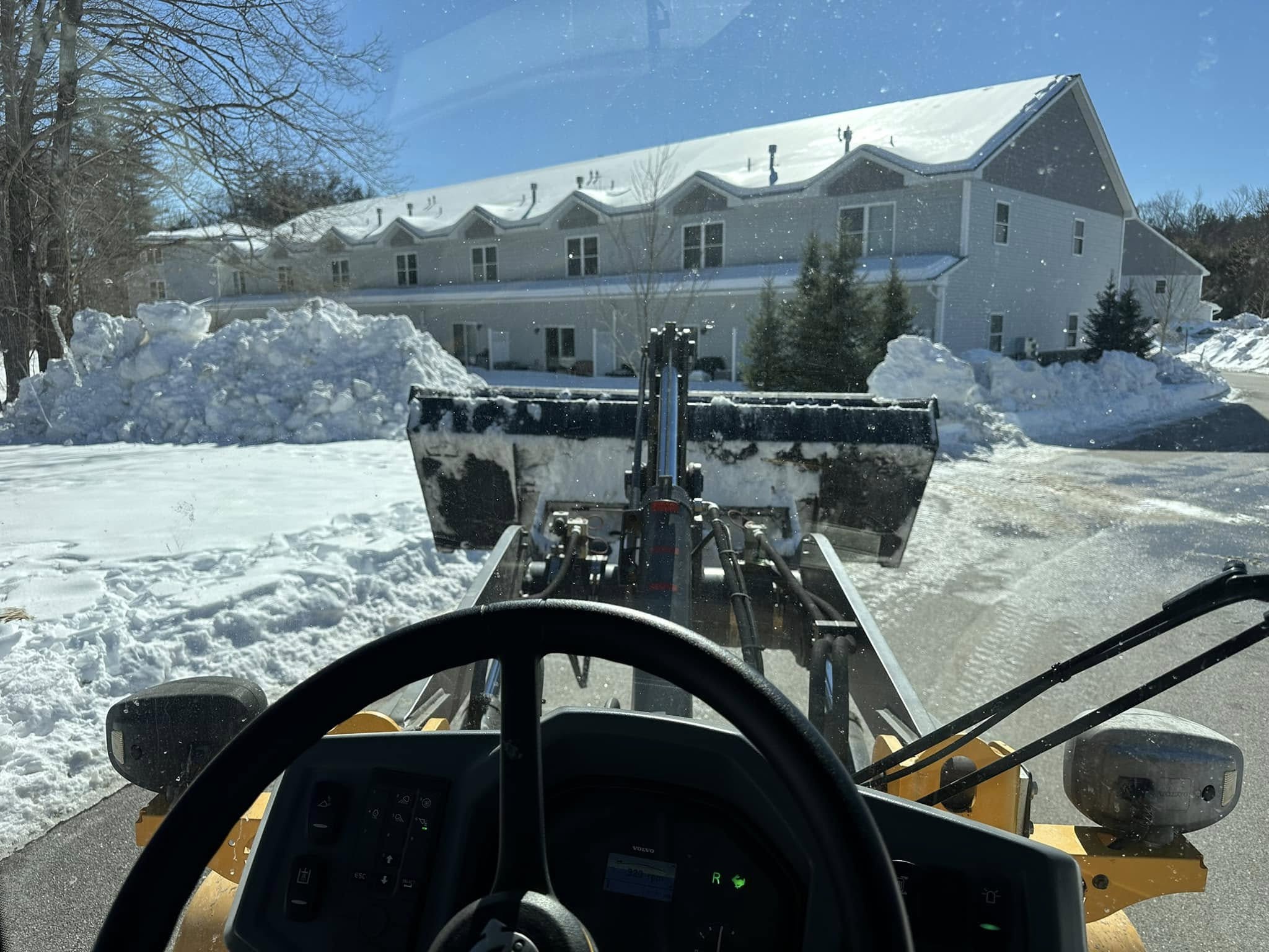 View from inside Kyle Poirier Landscaping LLC loader clearing snow at commercial property